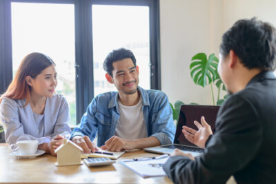 Real estate sales agent explain rental or buying condition to young couple before move to new home or apartment at real estate sales office.